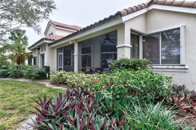 view of side of property featuring ceiling fan and a lawn