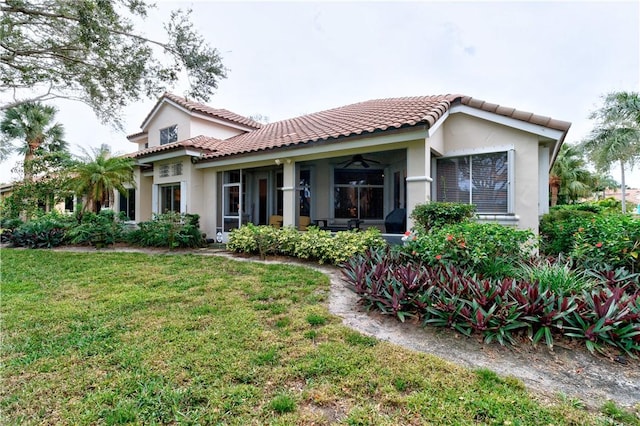 rear view of house with ceiling fan and a yard