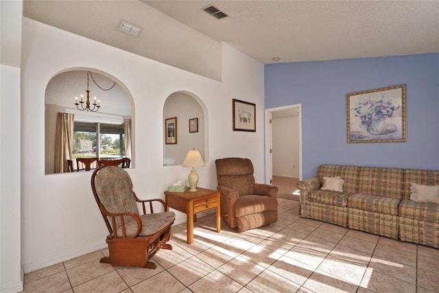 living room with a chandelier, a textured ceiling, vaulted ceiling, and light tile patterned flooring