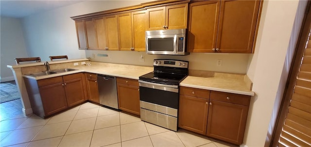 kitchen featuring sink, kitchen peninsula, light tile patterned floors, and stainless steel appliances