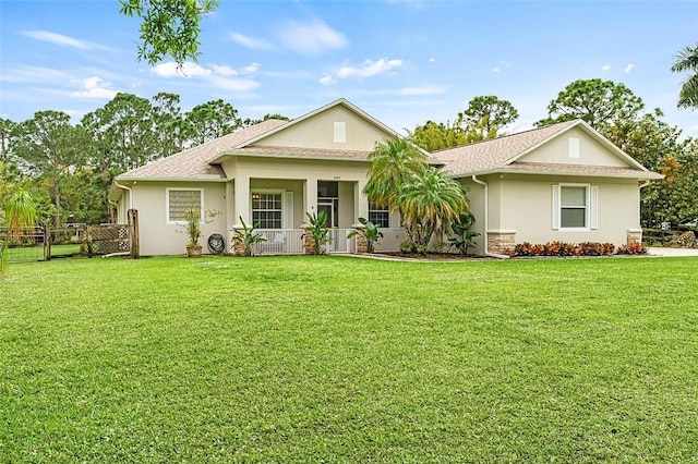 view of front of house with a porch, a front yard, fence, and stucco siding