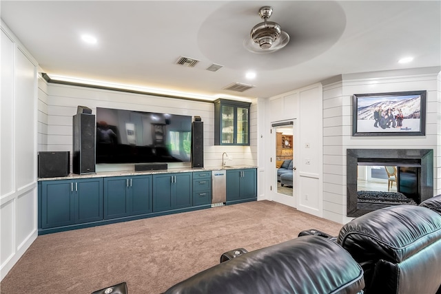 carpeted living room featuring a multi sided fireplace, sink, and ceiling fan