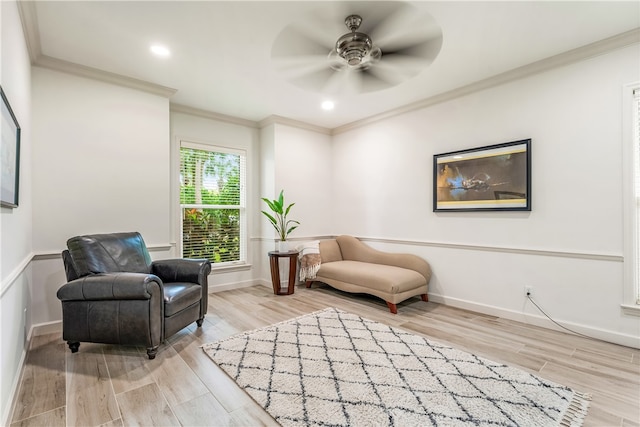 living area with light hardwood / wood-style floors, ceiling fan, and ornamental molding