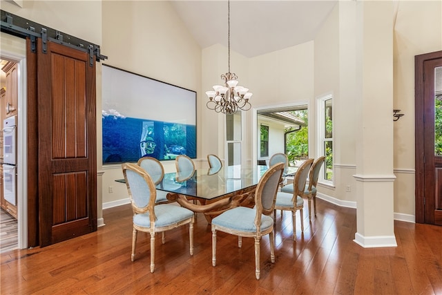 dining area featuring high vaulted ceiling, ornate columns, and hardwood / wood-style floors