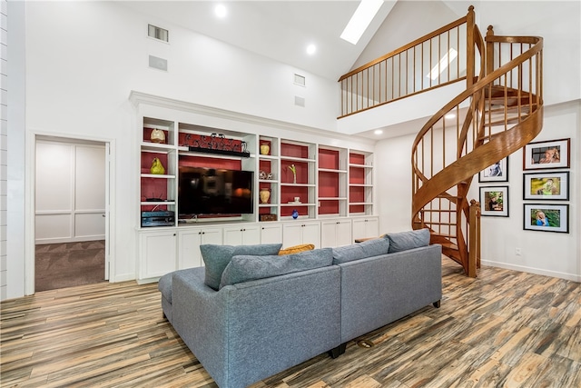 living room featuring high vaulted ceiling, hardwood / wood-style flooring, and a skylight