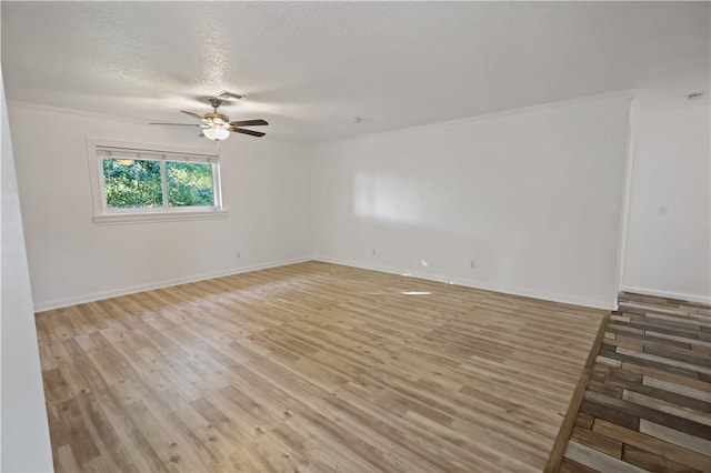 empty room with baseboards, visible vents, ceiling fan, a textured ceiling, and light wood-type flooring