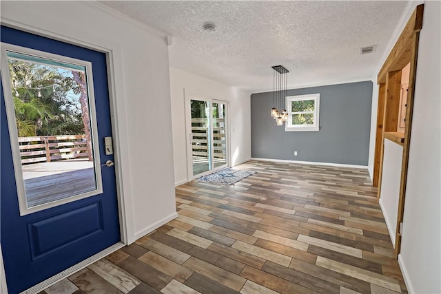 foyer entrance with a notable chandelier, wood finished floors, visible vents, and a textured ceiling