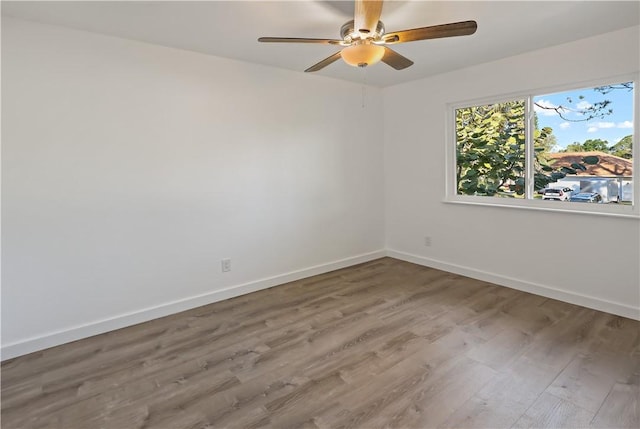 spare room featuring baseboards, wood finished floors, and ceiling fan