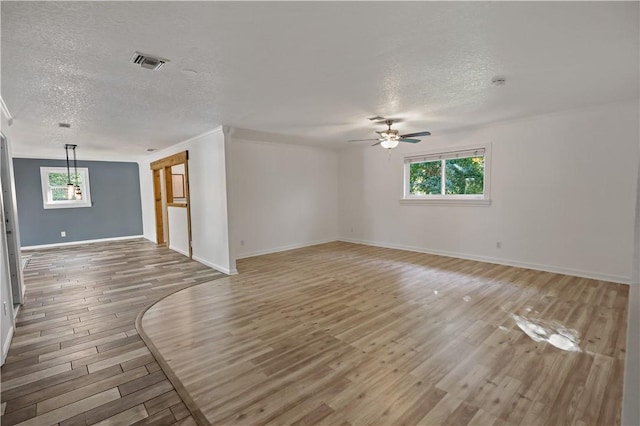 spare room with light wood finished floors, visible vents, ceiling fan, plenty of natural light, and a textured ceiling