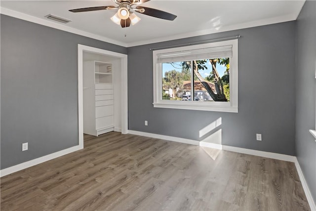 unfurnished bedroom featuring visible vents, a ceiling fan, wood finished floors, crown molding, and baseboards