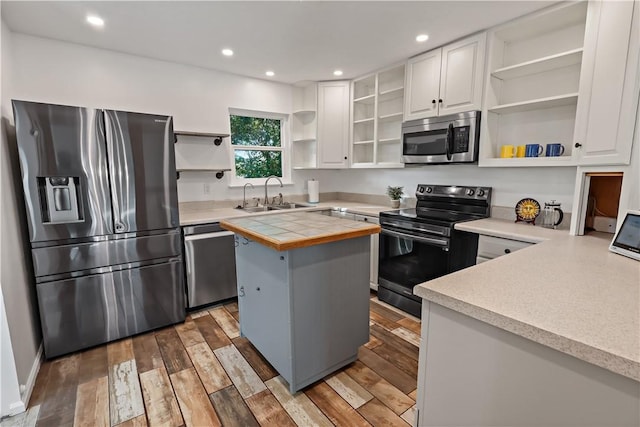 kitchen with wood finished floors, open shelves, a sink, white cabinets, and appliances with stainless steel finishes