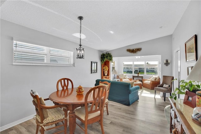 500 Grove Isle Cir Unit 202, Vero Beach, FL 32962 - dining area featuring vaulted ceiling, plenty of natural light, a chandelier, light wood-style floors, and a textured ceiling