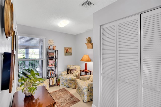 sitting room with a textured ceiling and light tile patterned floors