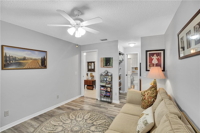 living room featuring ceiling fan, a textured ceiling, and light hardwood / wood-style flooring