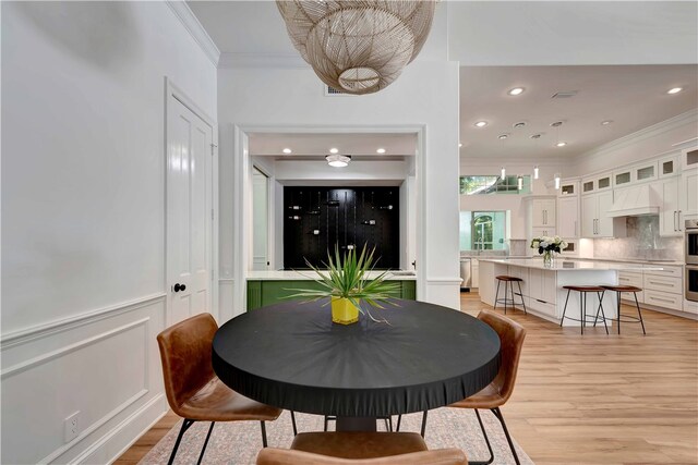 dining room with light wood-type flooring and crown molding