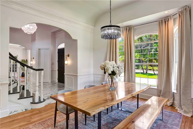 dining area with a chandelier, wood-type flooring, and ornamental molding