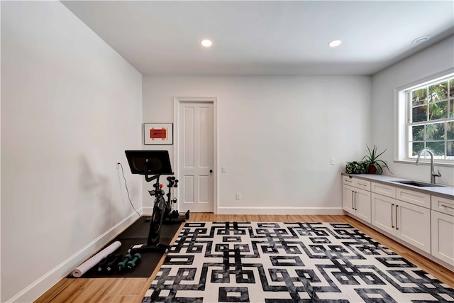 exercise room with light hardwood / wood-style flooring and sink