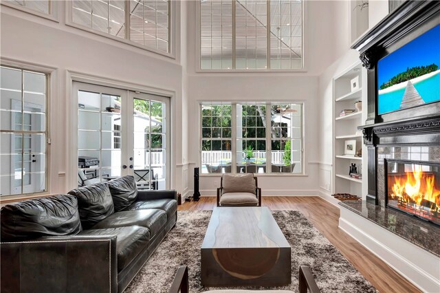 living room with a high ceiling, built in features, and light hardwood / wood-style flooring