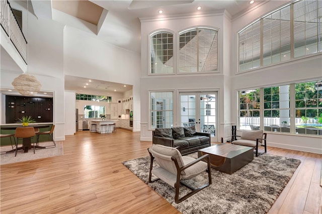 living room featuring a high ceiling, light hardwood / wood-style flooring, french doors, and ornamental molding