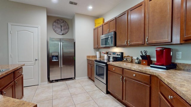 138 Port Royal Ct, Sebastian, FL 32958 - kitchen with appliances with stainless steel finishes, light tile patterned floors, brown cabinetry, light countertops, and recessed lighting