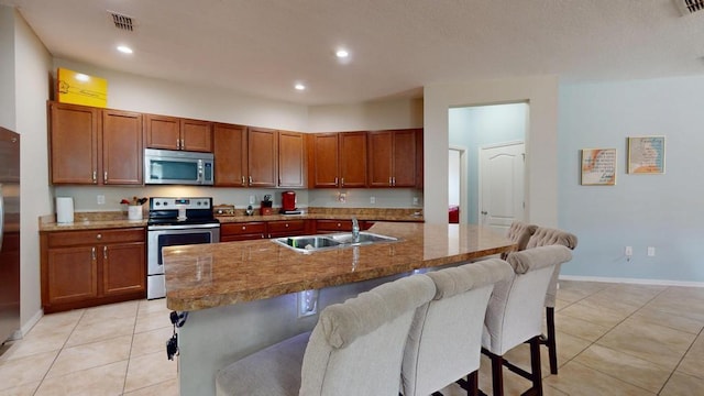 138 Port Royal Ct, Sebastian, FL 32958 - kitchen featuring appliances with stainless steel finishes, a breakfast bar area, light tile patterned floors, recessed lighting, and brown cabinets