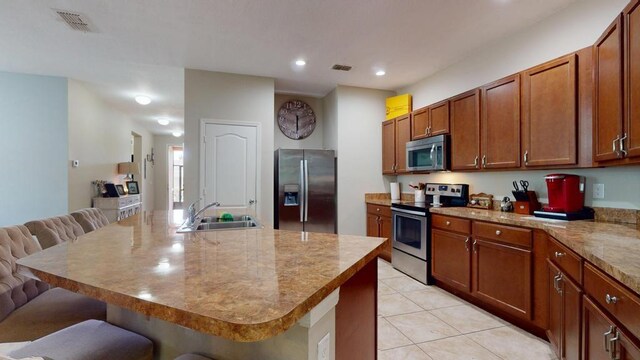 138 Port Royal Ct, Sebastian, FL 32958 - kitchen with stainless steel appliances, a breakfast bar, light tile patterned floors, brown cabinetry, and recessed lighting