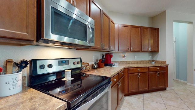 138 Port Royal Ct, Sebastian, FL 32958 - kitchen with appliances with stainless steel finishes, light countertops, brown cabinets, and light tile patterned floors