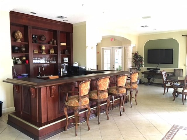 bar featuring light tile patterned floors, sink, and french doors