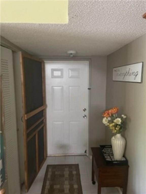 doorway to outside featuring light tile patterned floors and a textured ceiling