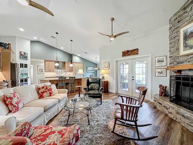 living room featuring a stone fireplace, french doors, high vaulted ceiling, ceiling fan, and dark hardwood / wood-style floors