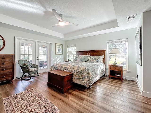 bedroom with multiple windows, wood-type flooring, ceiling fan, and a textured ceiling