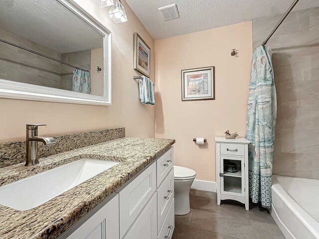 full bathroom featuring shower / tub combo with curtain, vanity, toilet, and a textured ceiling