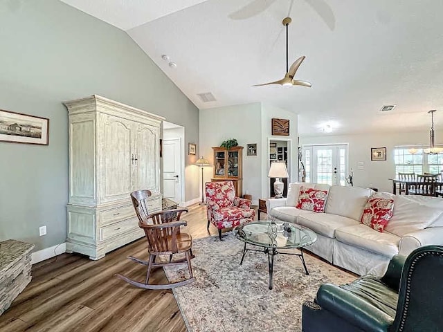 living room with dark hardwood / wood-style flooring, vaulted ceiling, and ceiling fan with notable chandelier