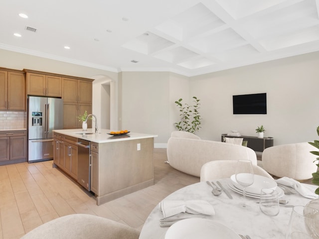 kitchen with stainless steel appliances, sink, tasteful backsplash, a kitchen island with sink, and light hardwood / wood-style flooring