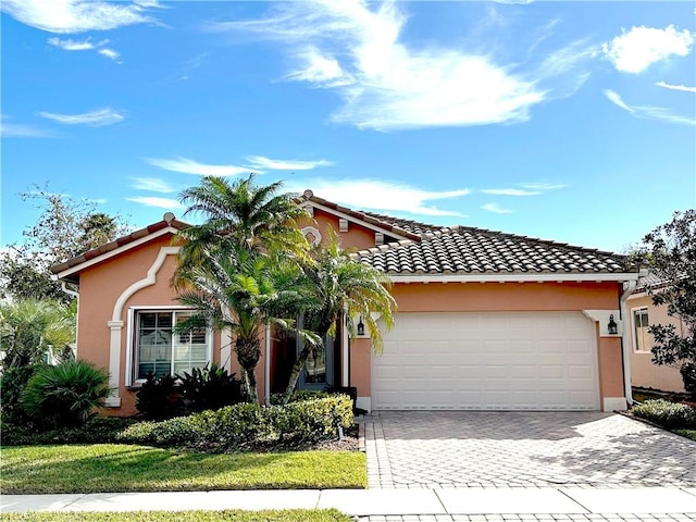 view of front of house with a garage, a tiled roof, decorative driveway, and stucco siding