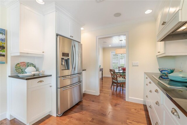 kitchen featuring light wood-style flooring, decorative backsplash, stainless steel refrigerator with ice dispenser, white cabinetry, and dark countertops