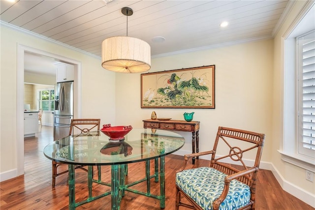 dining space featuring wood finished floors, baseboards, and ornamental molding