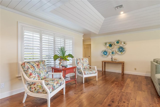 living area with visible vents, wood-type flooring, baseboards, and ornamental molding