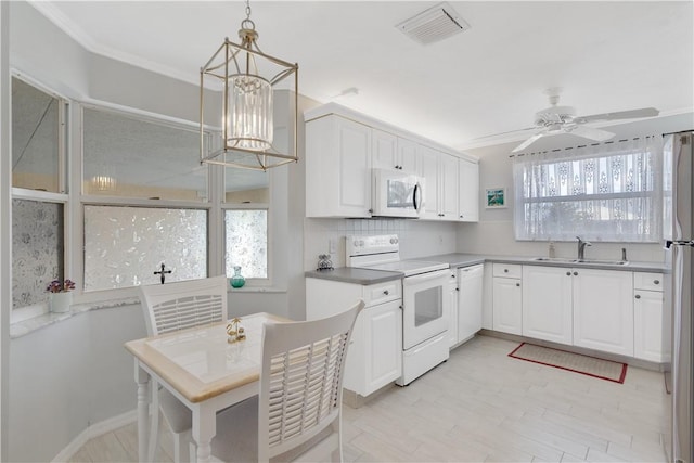 kitchen featuring white appliances, ceiling fan with notable chandelier, sink, pendant lighting, and white cabinets