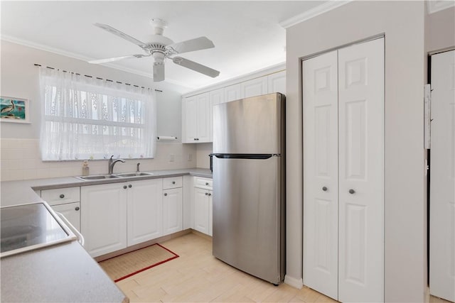 kitchen featuring stainless steel refrigerator, sink, backsplash, crown molding, and white cabinets