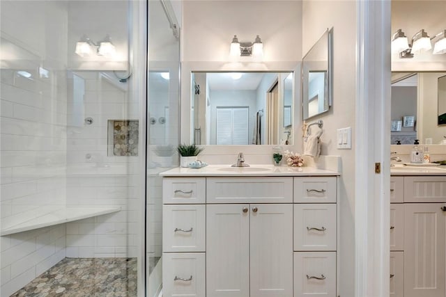 bathroom with a shower stall, two vanities, and a sink