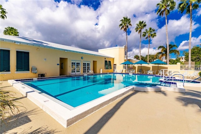 community pool with french doors, fence, and a patio