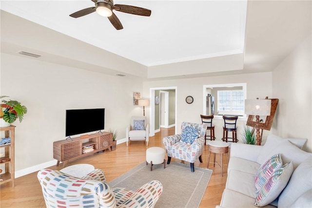 living area featuring baseboards, visible vents, and wood finished floors