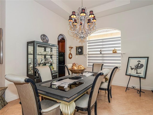 dining room with a raised ceiling, light tile patterned flooring, a notable chandelier, and baseboards