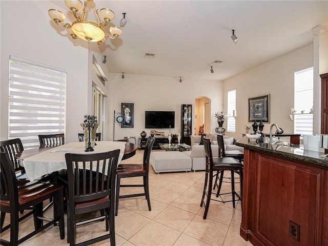 dining area with arched walkways, light tile patterned floors, visible vents, and a notable chandelier