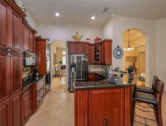 kitchen with stainless steel appliances, arched walkways, light tile patterned floors, and reddish brown cabinets