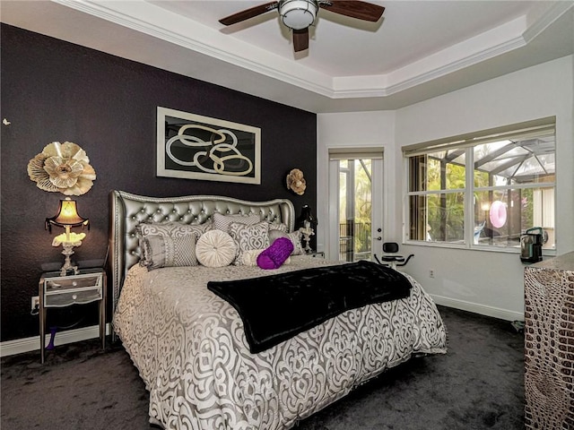 bedroom featuring ceiling fan, baseboards, ornamental molding, dark colored carpet, and a tray ceiling