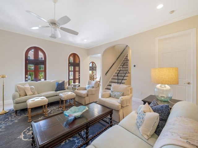 living room with arched walkways, stairway, baseboards, and crown molding