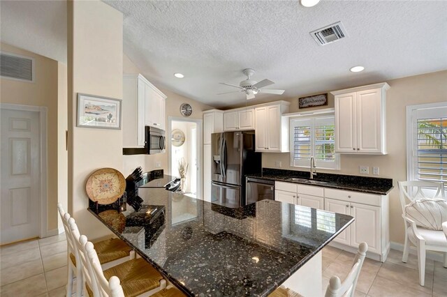 kitchen with appliances with stainless steel finishes, a sink, a peninsula, a kitchen bar, and white cabinetry