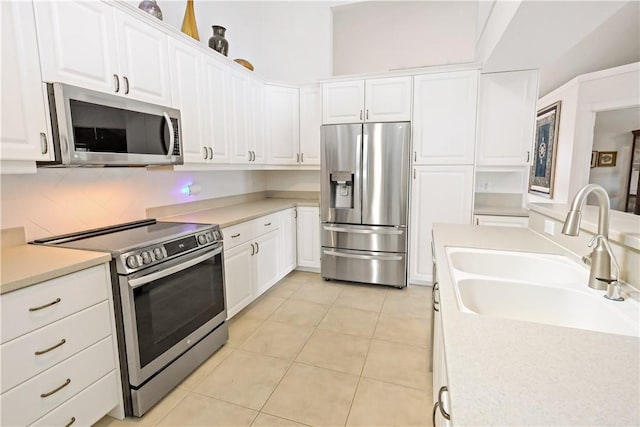 kitchen with light tile patterned flooring, sink, white cabinets, stainless steel appliances, and backsplash